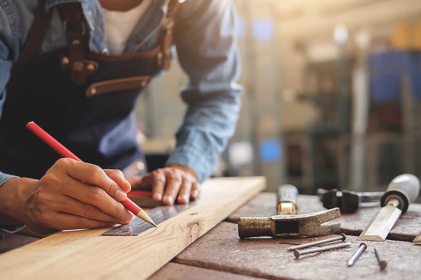 Mitarbeiter misst Holz präzise aus bei Handwerksarbeiten