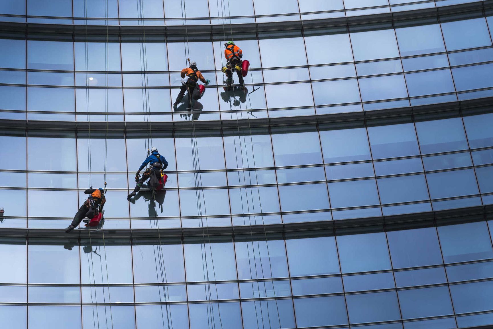 Vier Reinigungskräfte bei der professionellen Glasreinigung an einer Gebäudefassade