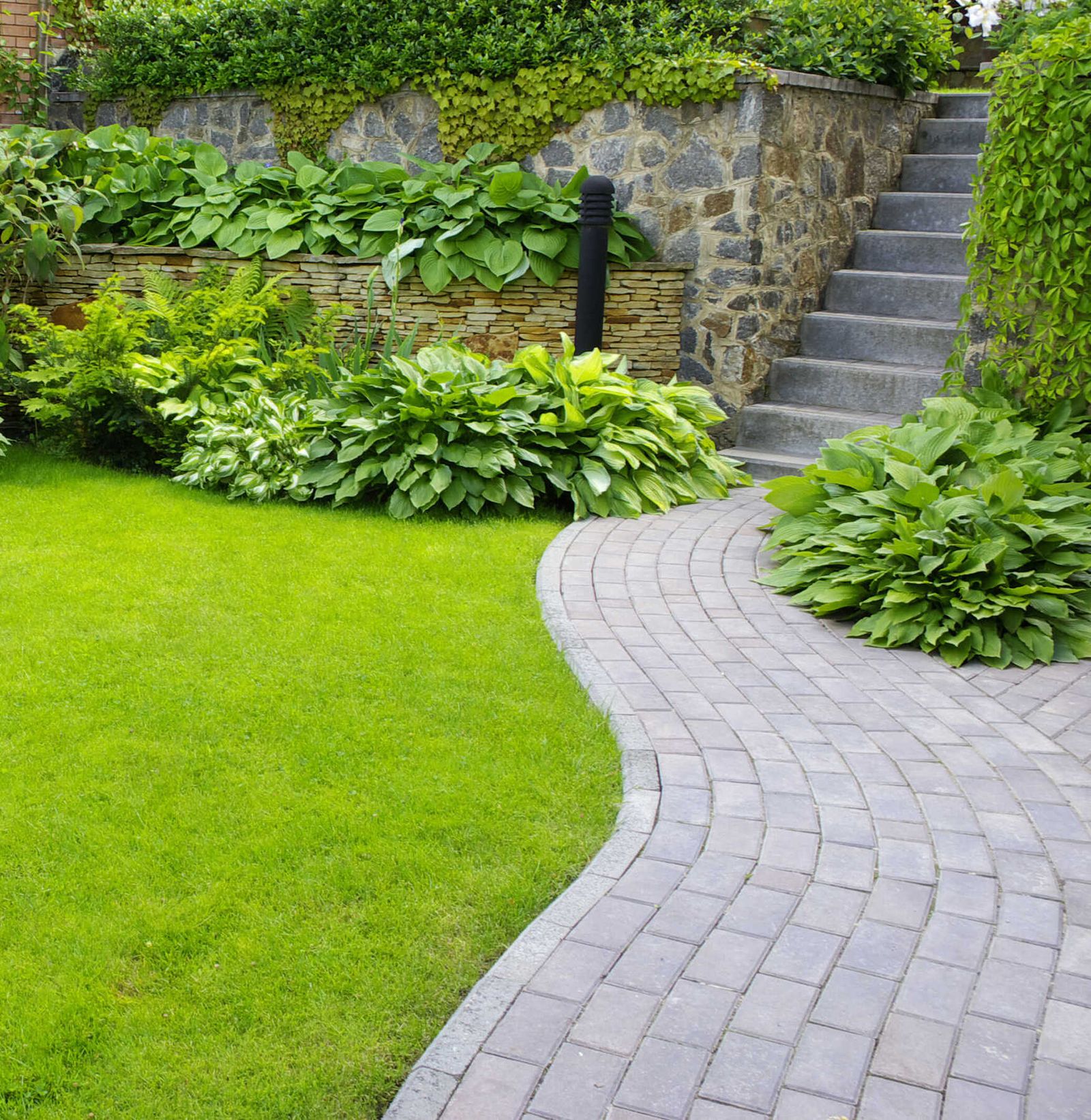 Neu angelegter Garten mit Pflastersteinen und gestalteter Außentreppe